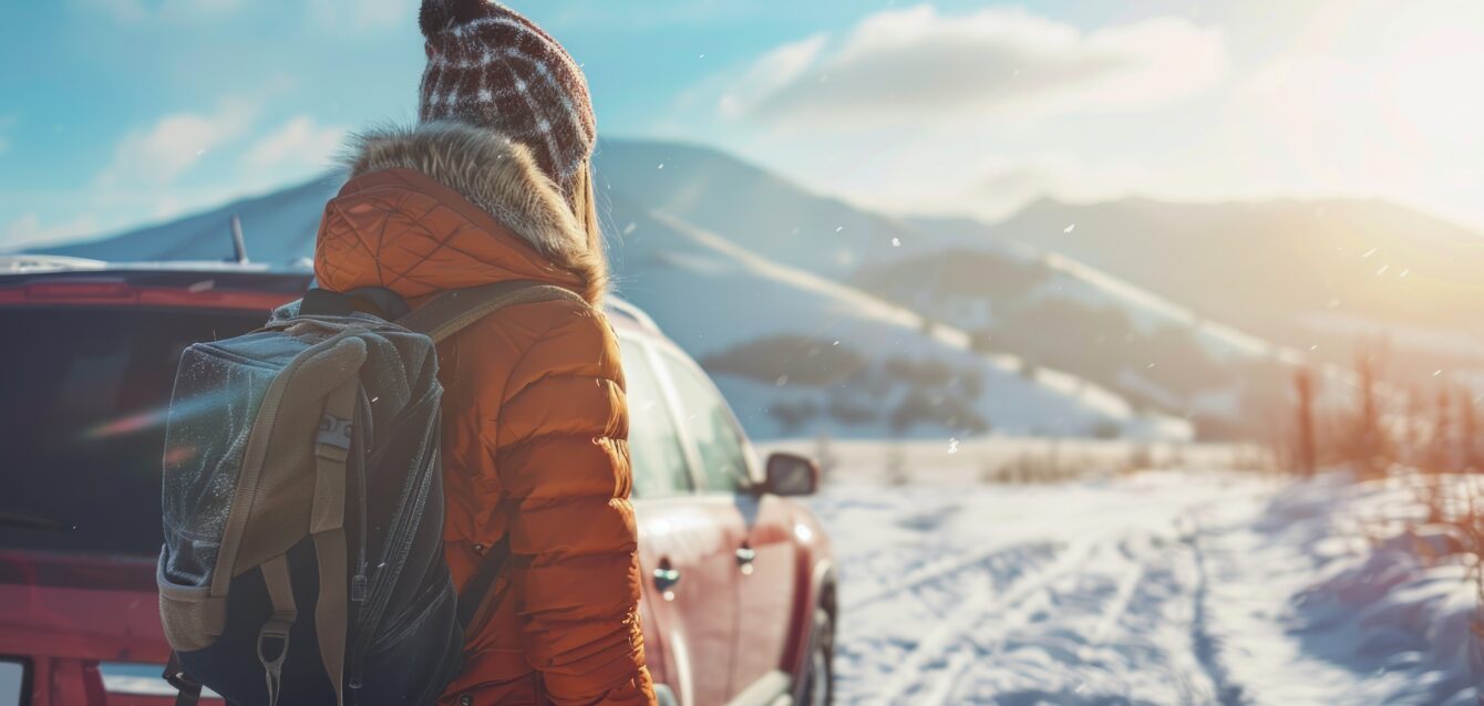 Woman traveling standing near the car in the mountains winter at sunny day. Generated AI image